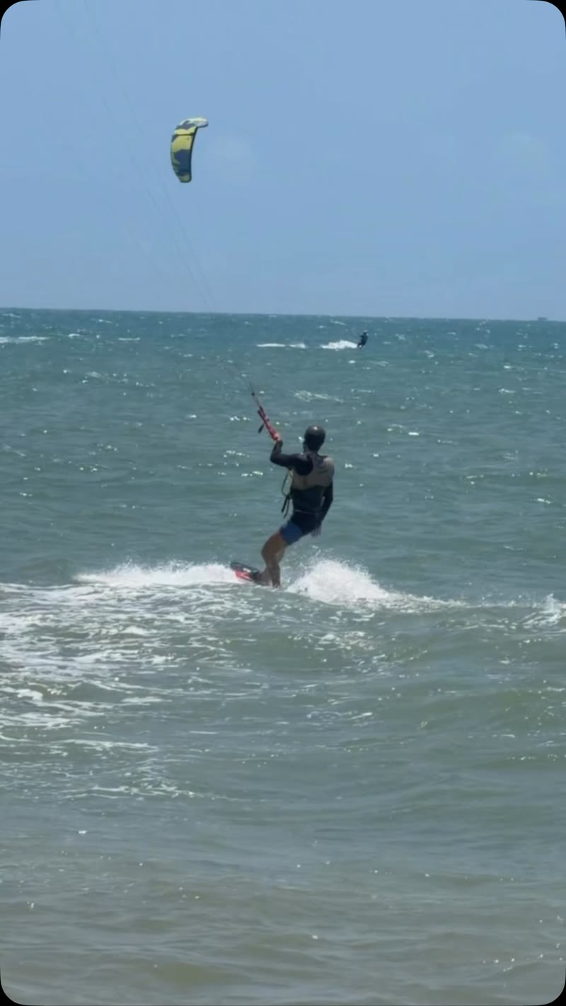 Aluno velejando sozinho no mar de Cumbuco com o kite amarelo no céu
